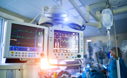 an intensive care ward in a hospital with monitoring screens and staff in blue gowns